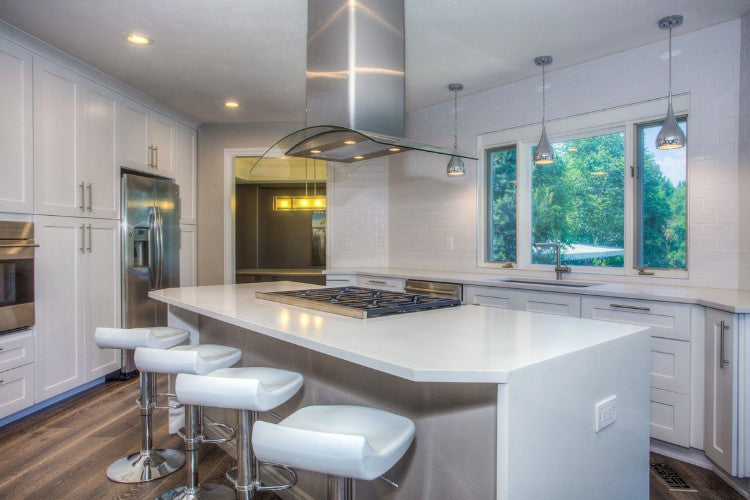 Modern kitchen with white island, stools, and stainless steel appliances.